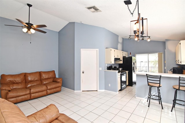 kitchen featuring ceiling fan with notable chandelier, electric range, a breakfast bar area, hanging light fixtures, and light tile patterned floors