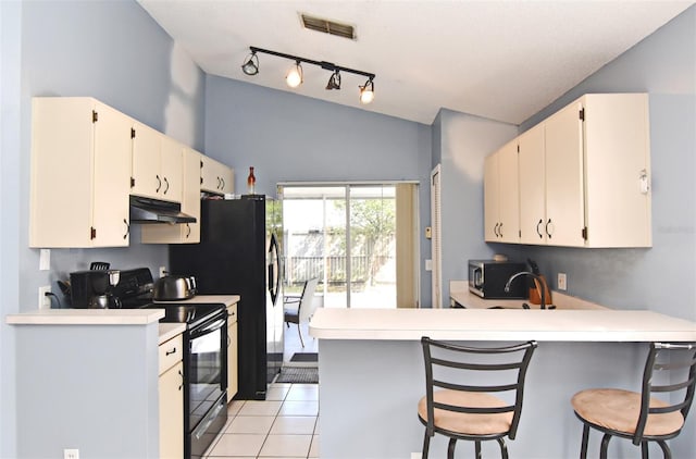 kitchen with black electric range oven, lofted ceiling, kitchen peninsula, light tile patterned floors, and a breakfast bar