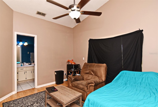 bedroom featuring ensuite bathroom, light wood-type flooring, a textured ceiling, ceiling fan, and lofted ceiling