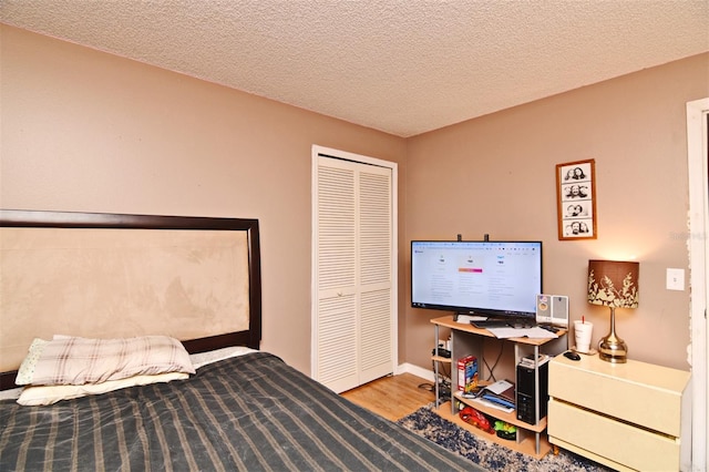 bedroom with a closet, wood-type flooring, and a textured ceiling