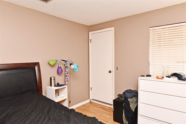 bedroom with a textured ceiling and light hardwood / wood-style floors