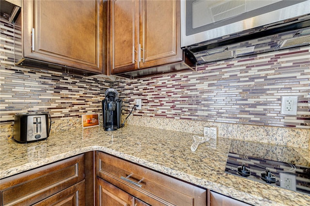 kitchen with decorative backsplash, gas cooktop, and light stone countertops