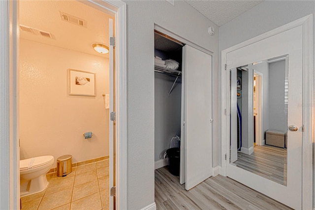 bathroom featuring toilet, wood-type flooring, and a textured ceiling