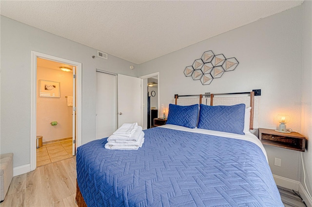 bedroom with hardwood / wood-style floors, ensuite bathroom, a textured ceiling, and a closet