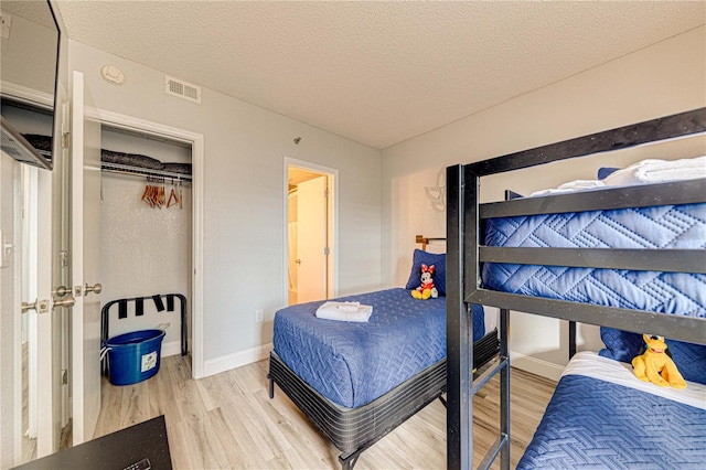 bedroom with hardwood / wood-style floors, a textured ceiling, and a closet