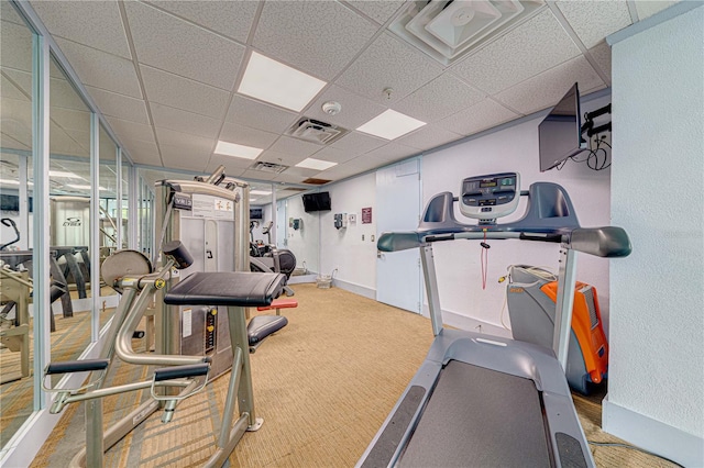 gym featuring a paneled ceiling and light carpet