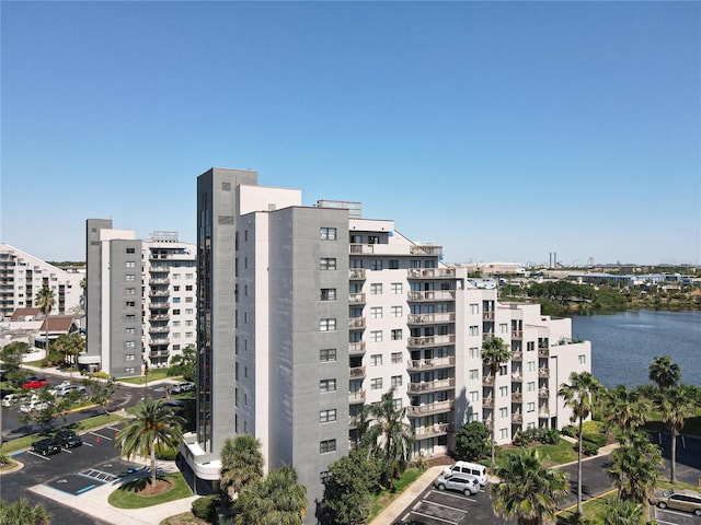 view of building exterior featuring uncovered parking, a view of city, and a water view