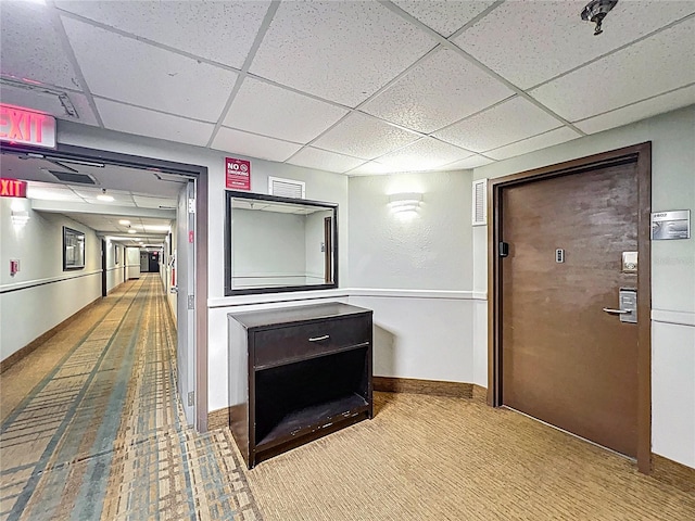 corridor with carpet flooring, a drop ceiling, and baseboards
