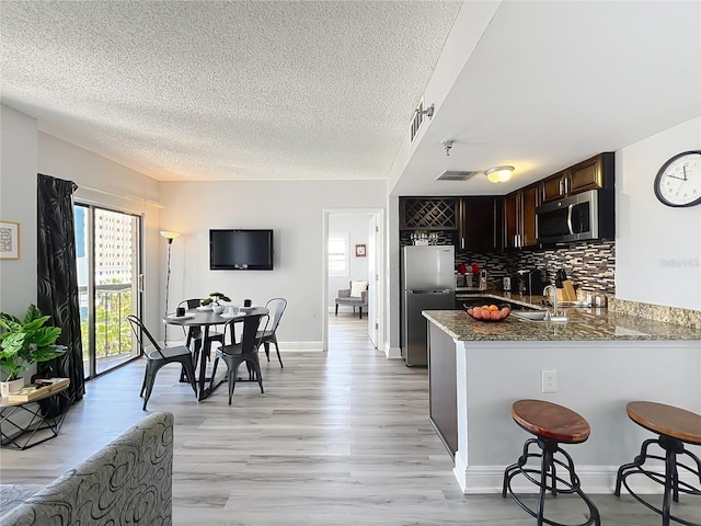 kitchen featuring tasteful backsplash, a textured ceiling, appliances with stainless steel finishes, and stone counters