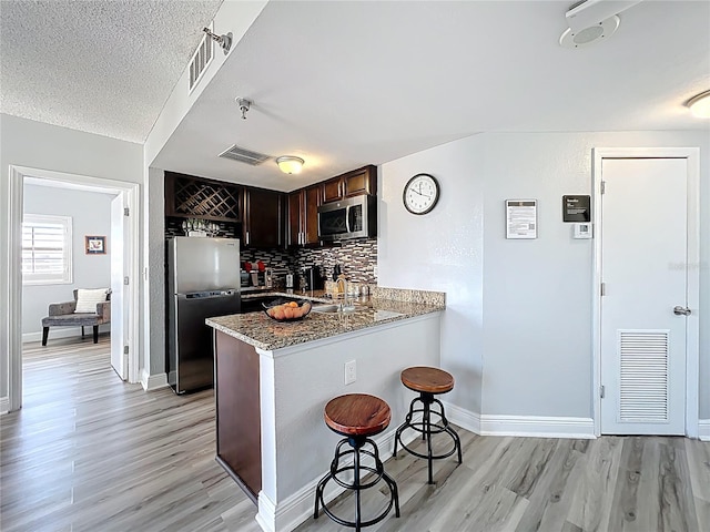 kitchen with visible vents, light wood finished floors, a breakfast bar area, and stainless steel appliances