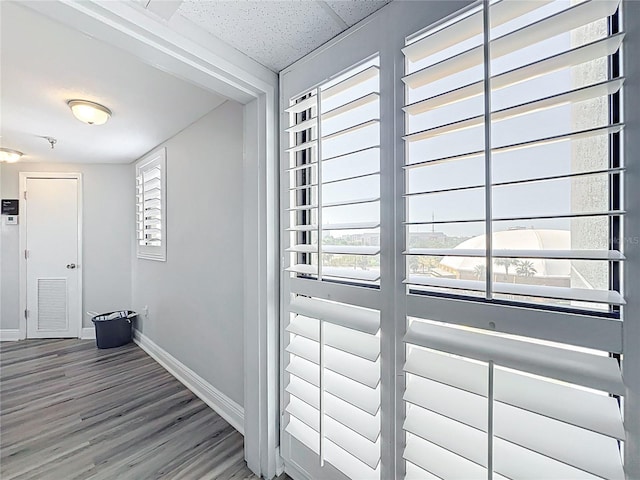 hallway featuring visible vents, baseboards, and wood finished floors