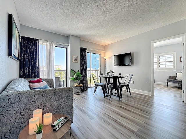 living room featuring light wood-style flooring, a textured ceiling, and baseboards