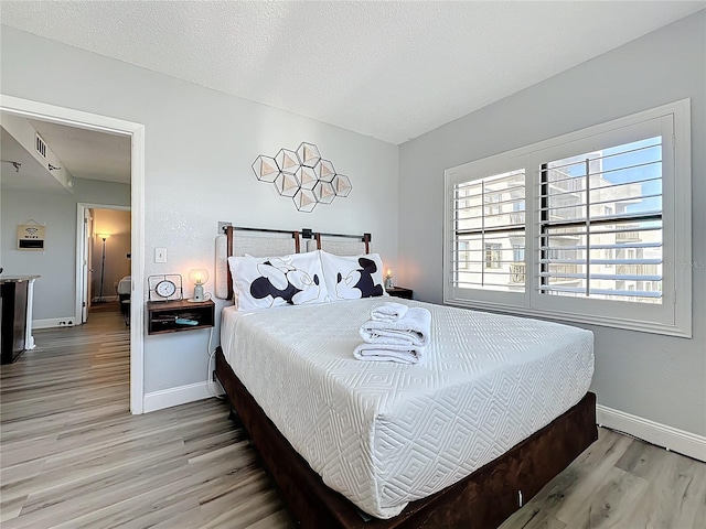 bedroom with light wood-style flooring, baseboards, and visible vents
