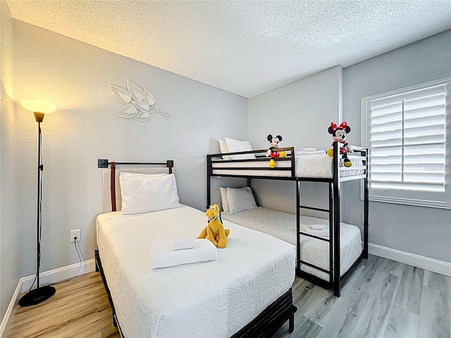 bedroom with a textured ceiling, wood finished floors, and baseboards