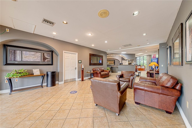 living area featuring recessed lighting, arched walkways, visible vents, and baseboards