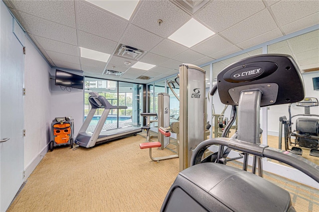 exercise room with carpet flooring, baseboards, a drop ceiling, and visible vents
