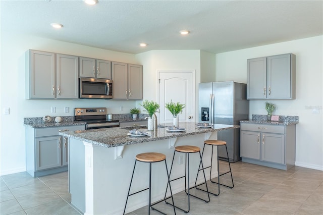 kitchen with a kitchen bar, sink, an island with sink, and stainless steel appliances