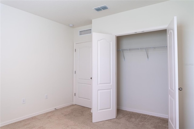 unfurnished bedroom featuring light carpet and a closet