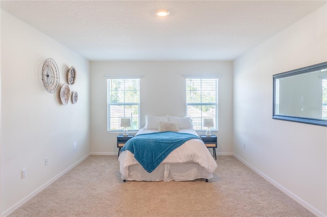 bedroom with a textured ceiling and light colored carpet