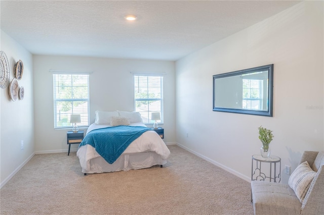 bedroom with a textured ceiling and light colored carpet