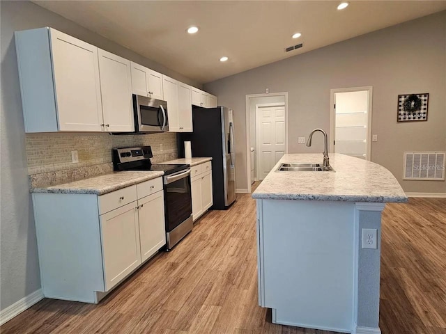 kitchen featuring lofted ceiling, a center island with sink, appliances with stainless steel finishes, light hardwood / wood-style floors, and sink