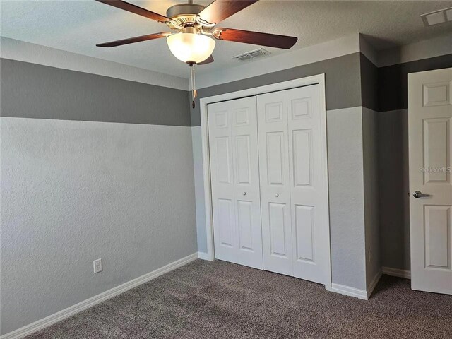 unfurnished bedroom with a closet, ceiling fan, and dark colored carpet