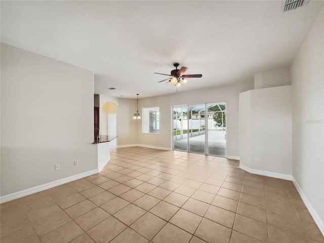 tiled spare room with ceiling fan with notable chandelier