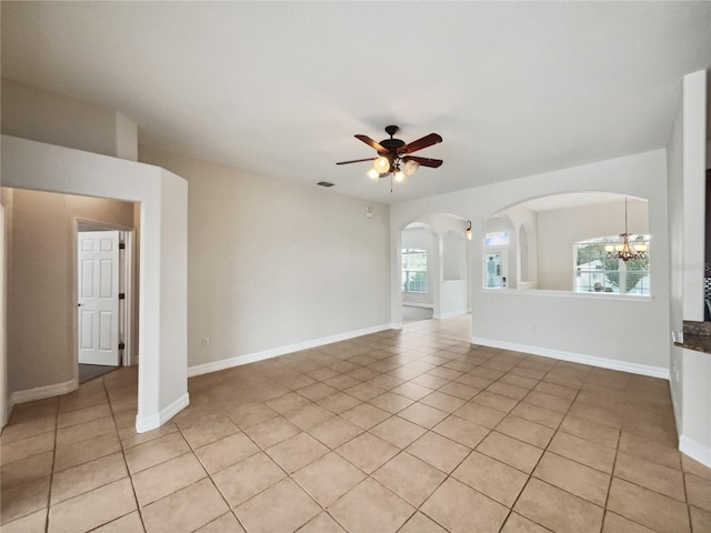 tiled empty room featuring ceiling fan with notable chandelier