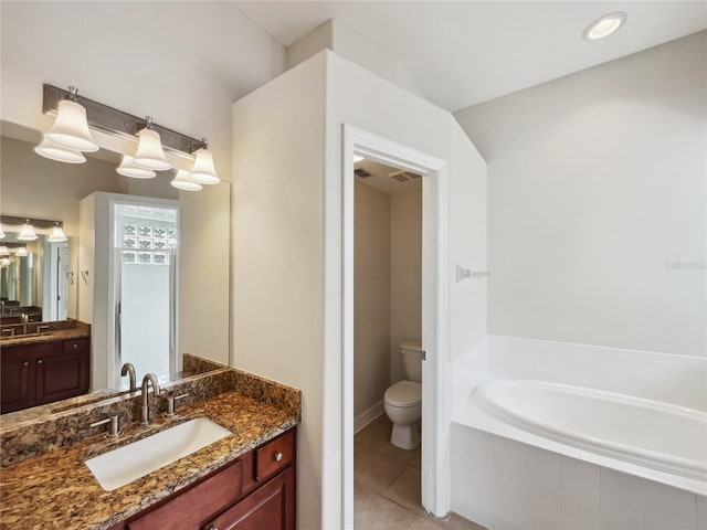 bathroom featuring tile patterned flooring, vanity, tiled bath, and toilet