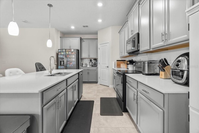 kitchen with gray cabinetry, backsplash, sink, decorative light fixtures, and appliances with stainless steel finishes