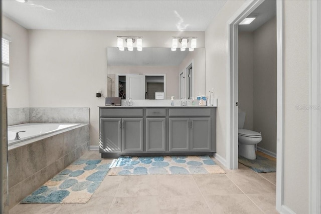 bathroom featuring a textured ceiling, toilet, vanity, tiled bath, and tile patterned flooring