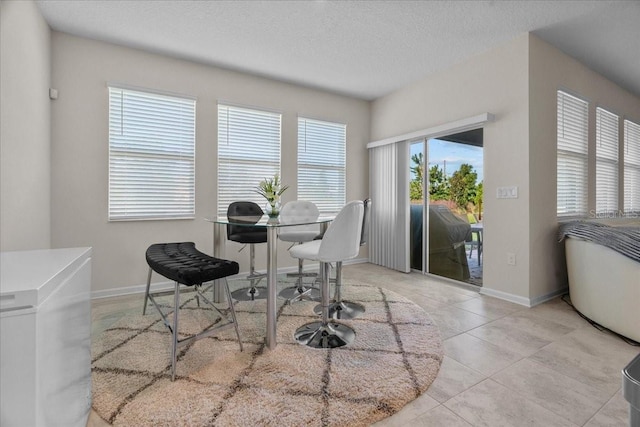 tiled dining space with a textured ceiling and a healthy amount of sunlight