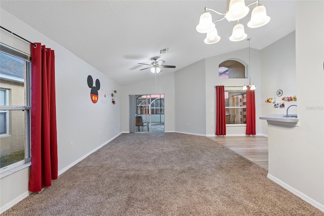 unfurnished living room featuring light carpet, vaulted ceiling, and a wealth of natural light