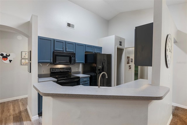 kitchen with kitchen peninsula, black appliances, sink, light wood-type flooring, and blue cabinetry