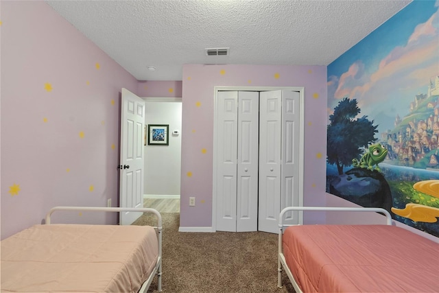 bedroom with a textured ceiling, carpet floors, and a closet