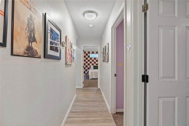 corridor with light hardwood / wood-style flooring and a textured ceiling