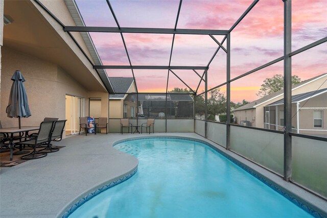 pool at dusk featuring a patio area and a lanai