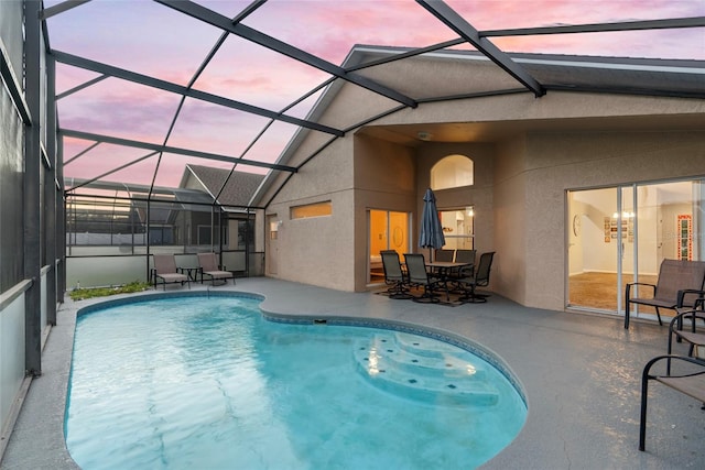 pool at dusk featuring a patio area and glass enclosure