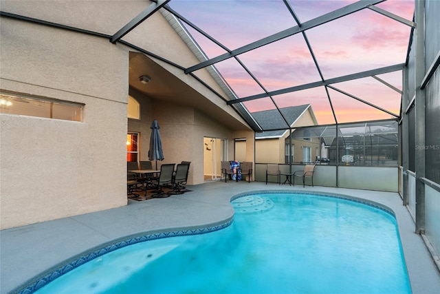 pool at dusk featuring a patio area and glass enclosure