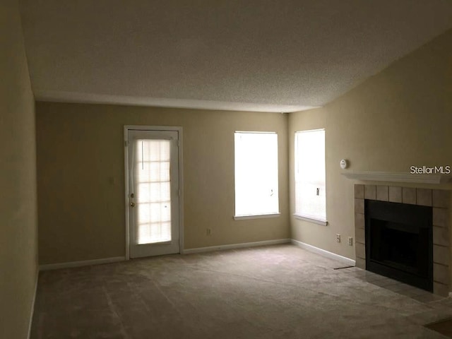 unfurnished living room with a fireplace, a textured ceiling, and carpet floors