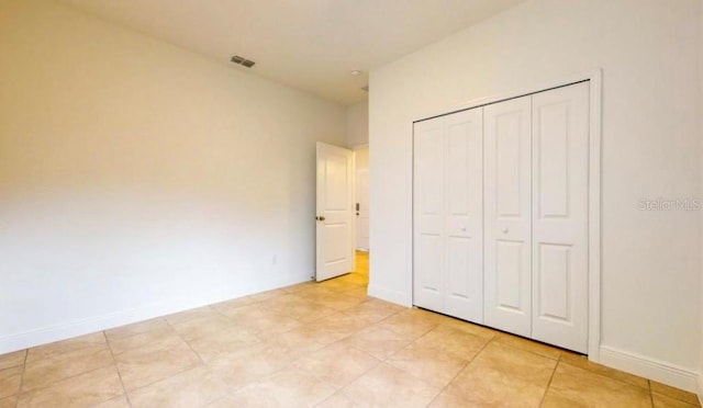 unfurnished bedroom with light tile patterned flooring and a closet