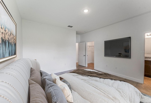 bedroom with a spacious closet, ensuite bath, a closet, and light tile patterned floors