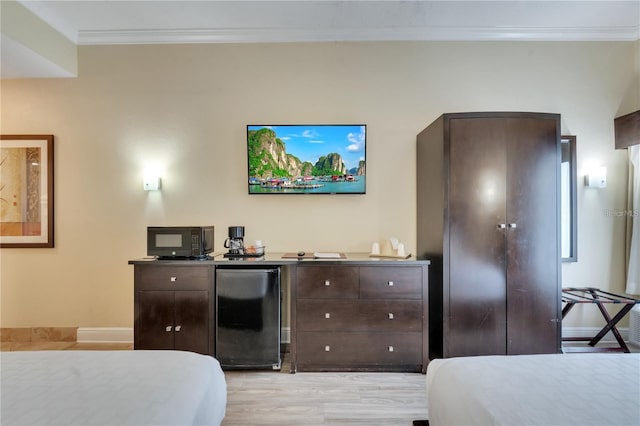 bedroom with crown molding, light hardwood / wood-style flooring, and black fridge