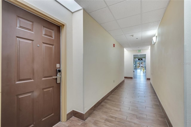 hallway featuring a paneled ceiling and light hardwood / wood-style floors