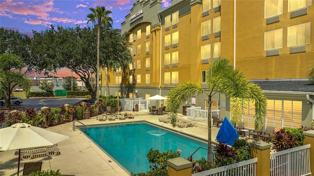 pool at dusk featuring a patio