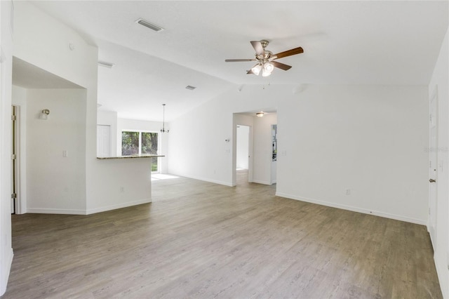 unfurnished living room with lofted ceiling, hardwood / wood-style flooring, and ceiling fan with notable chandelier