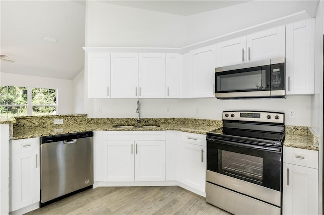 kitchen with stone countertops, white cabinetry, and stainless steel appliances