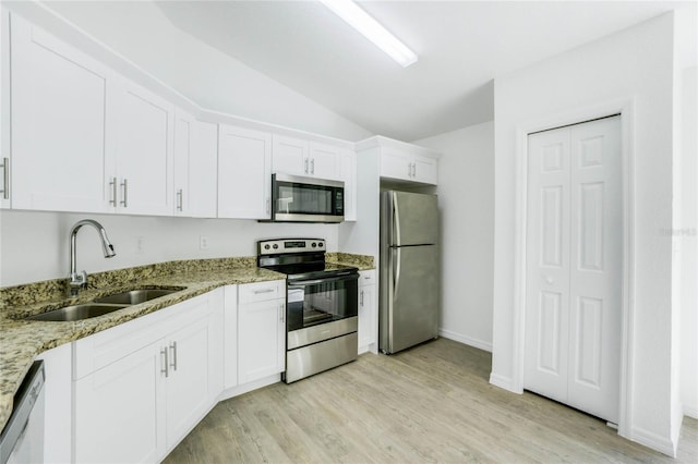 kitchen with appliances with stainless steel finishes, sink, light wood-type flooring, vaulted ceiling, and white cabinets