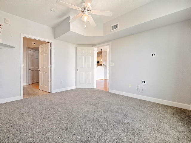 unfurnished bedroom featuring visible vents, baseboards, ceiling fan, and light carpet