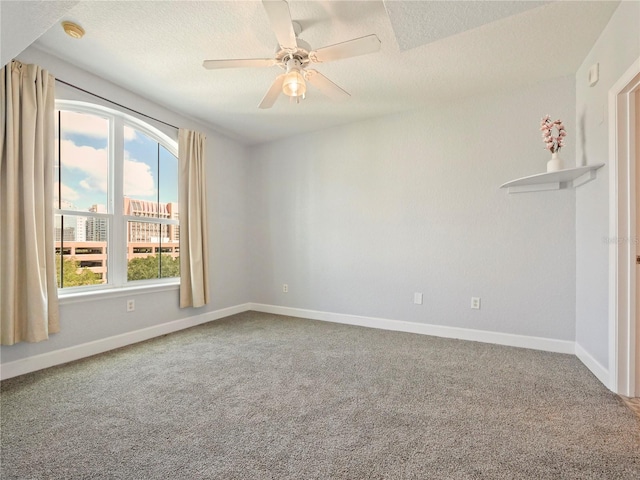 carpeted spare room with a textured ceiling and ceiling fan